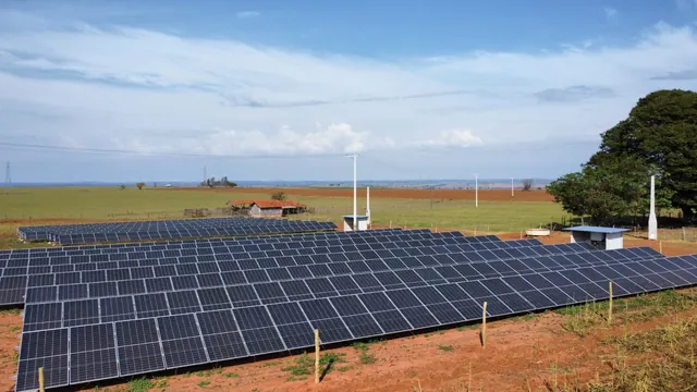 Usina fotovoltaica da Linus em terra vermelha, com casa de inversores e celeiro ao fundo.